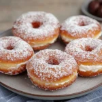 Homemade stuffed donuts with hazelnut filling dusted with sugar, one cut open